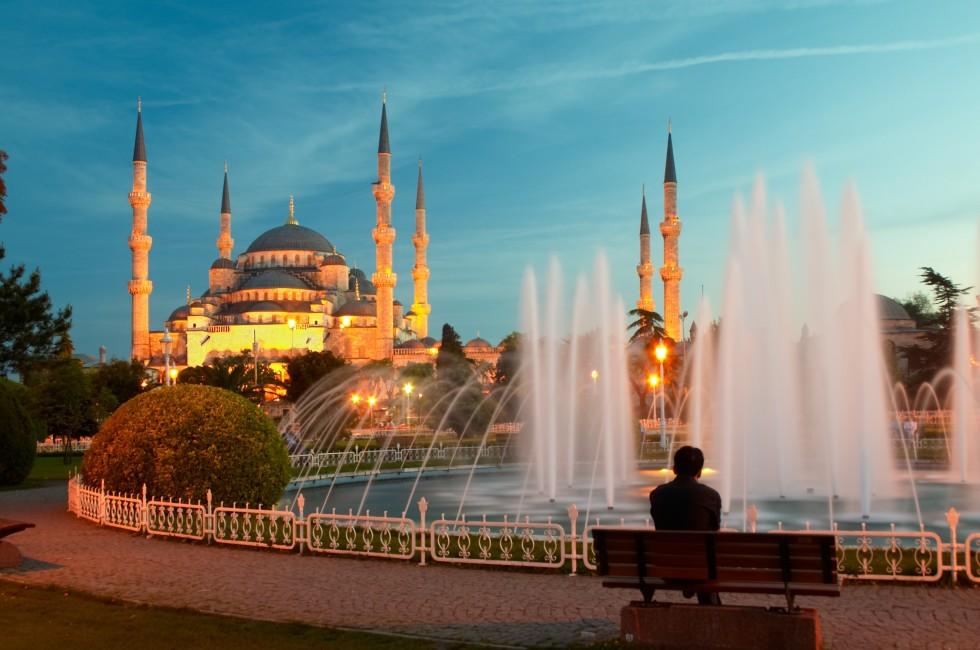 Man sitting on a bench opposite of blue mosque in Istanbul.
