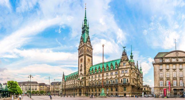Beautiful view of famous Hamburg town hall with dramatic clouds and blue sky at market square near lake Binnenalster in Altstadt quarter, Hamburg, Germany.