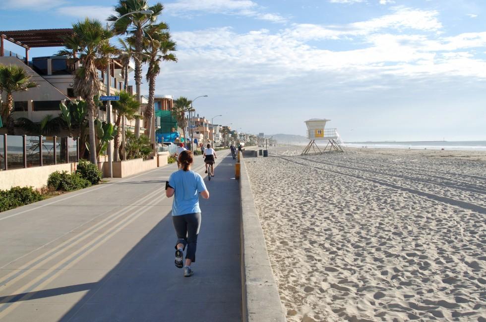 Joggers and cyclists on bicycle path and walkway along a beach; Mission Beach; San Diego, California.