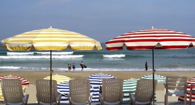 Striped umbrellas on the beach, facing the ocean, Biarritz, France.