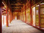 Red doors, wall panels, and ceiling, painted with gold, provide a dramatic hallway in a building of the Imperial Citadel in the city of Hue, central Vietnam.