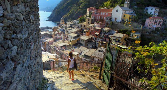 Young woman walking on stairs of small street of Vernazza town. 