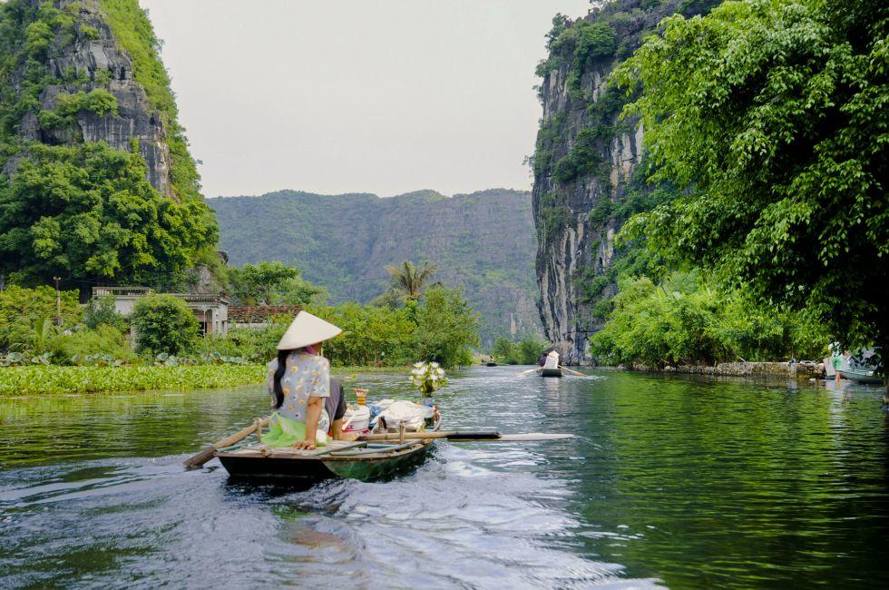 The woman is paddling groceries and fresh flowers boat. Tam Coc Grotto, Ninh Binh Province, Vietnam; Shutterstock ID 108993764; Project/Title: fodors.com destinations; Downloader: Melanie Marin