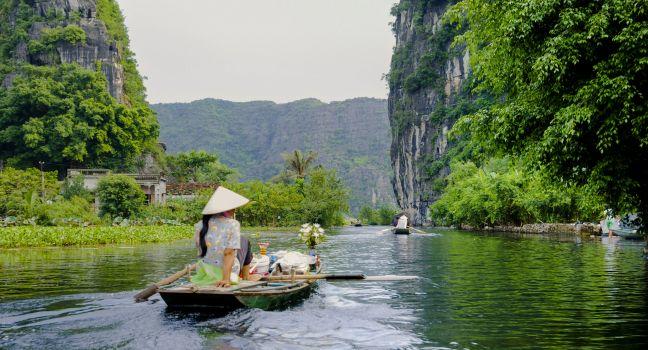 The woman is paddling groceries and fresh flowers boat. Tam Coc Grotto, Ninh Binh Province, Vietnam; Shutterstock ID 108993764; Project/Title: fodors.com destinations; Downloader: Melanie Marin