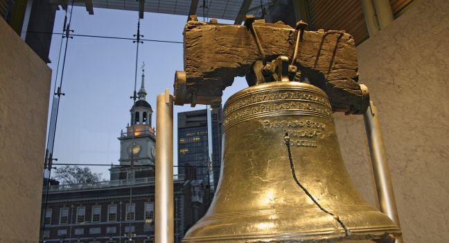 Close-up shot of the Liberty Bell with Independence Hall in the background at dusk. Located in downtown Philadelphia