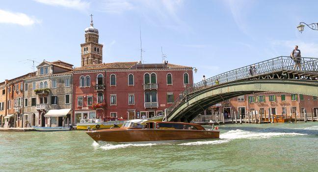 View of a canal with a bridge and a wooden boat on Murano, Venice, Italy. 